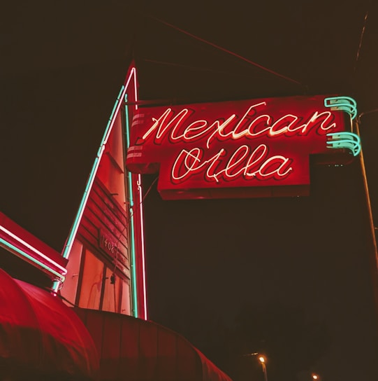 A vibrant illuminated storefront sign glowing at dusk in El Paso.