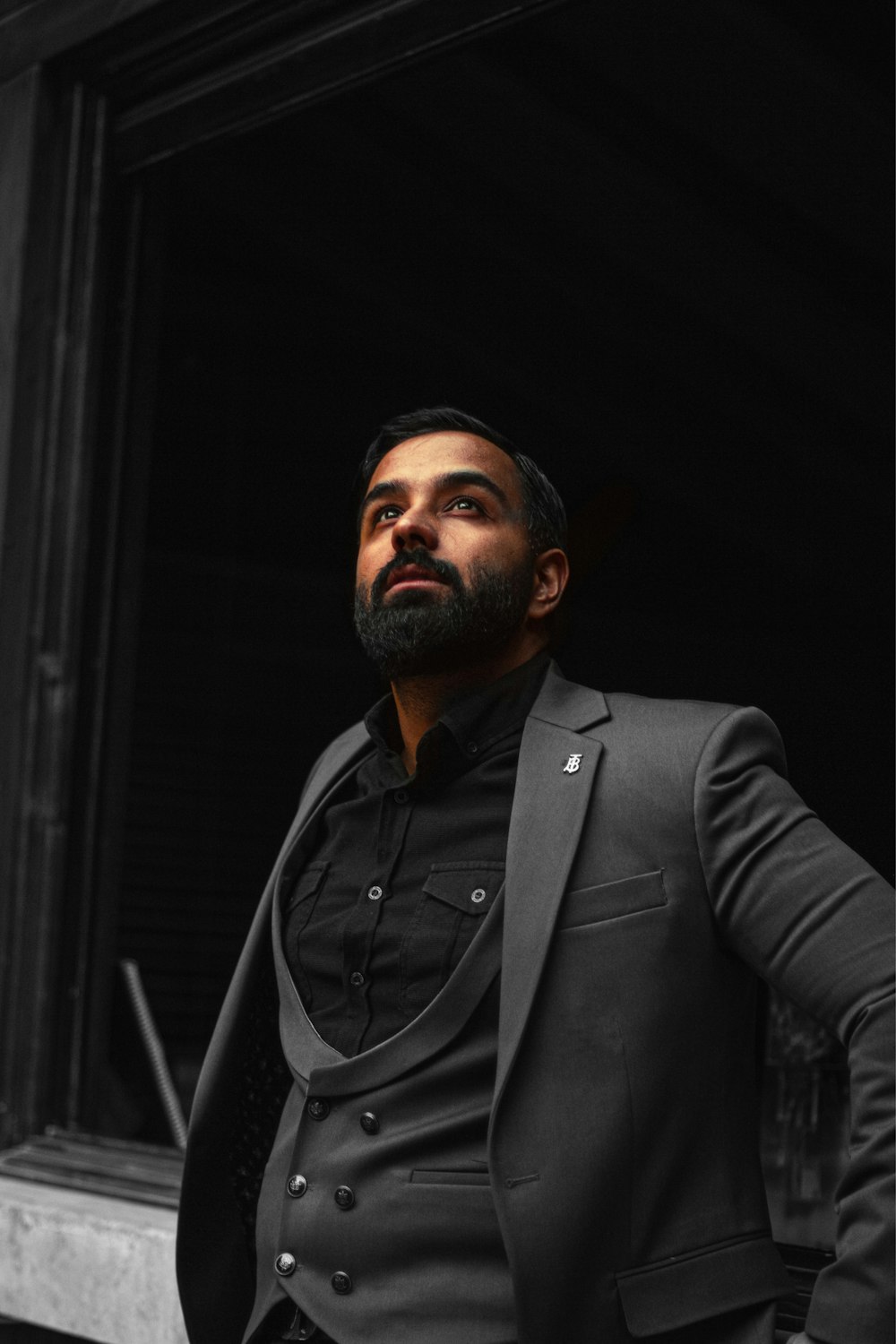 a man in a tuxedo standing in front of a window