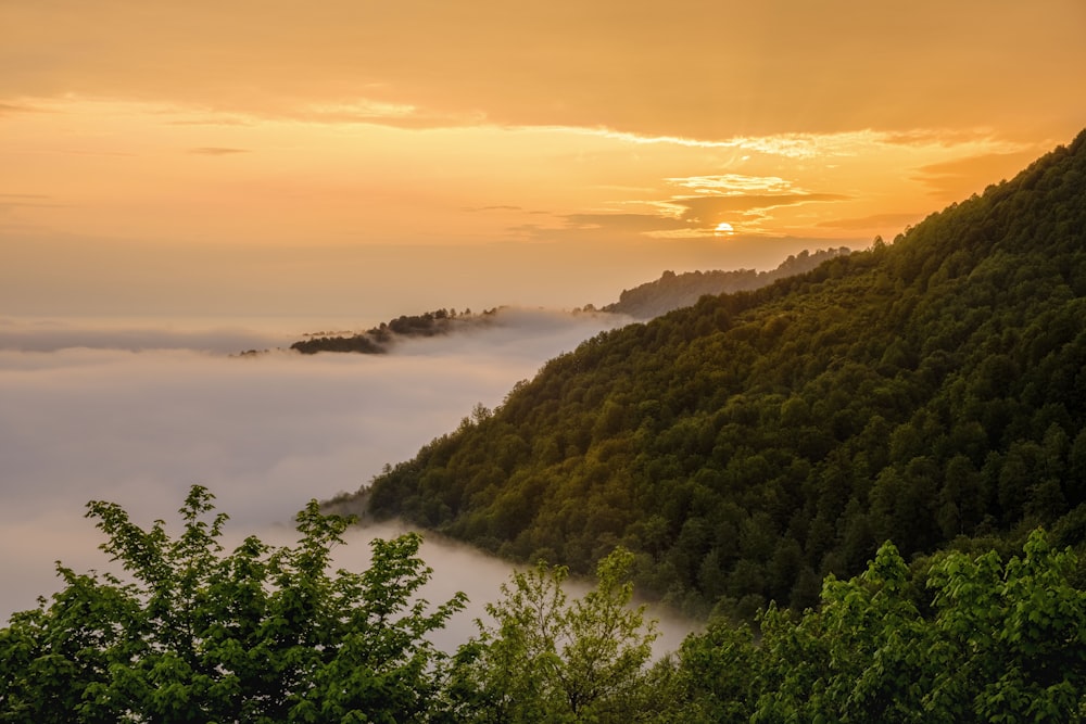 the sun is setting over a foggy valley