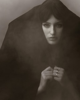 Lifestyle shot of a person wearing multiple Atalaia amulets in a softly lit, mysterious setting