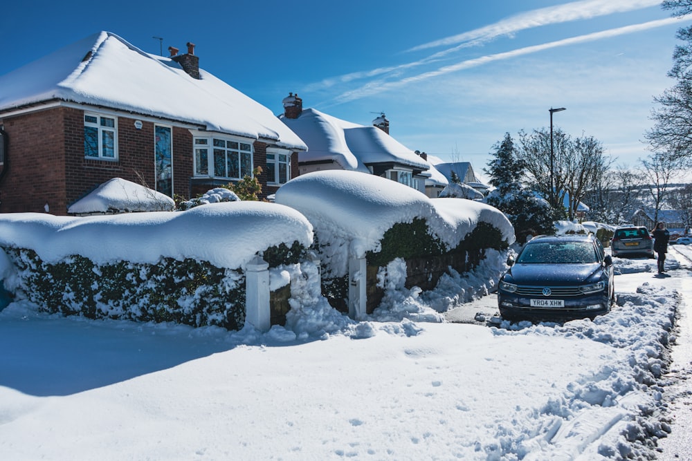 a car is parked in front of a house covered in snow