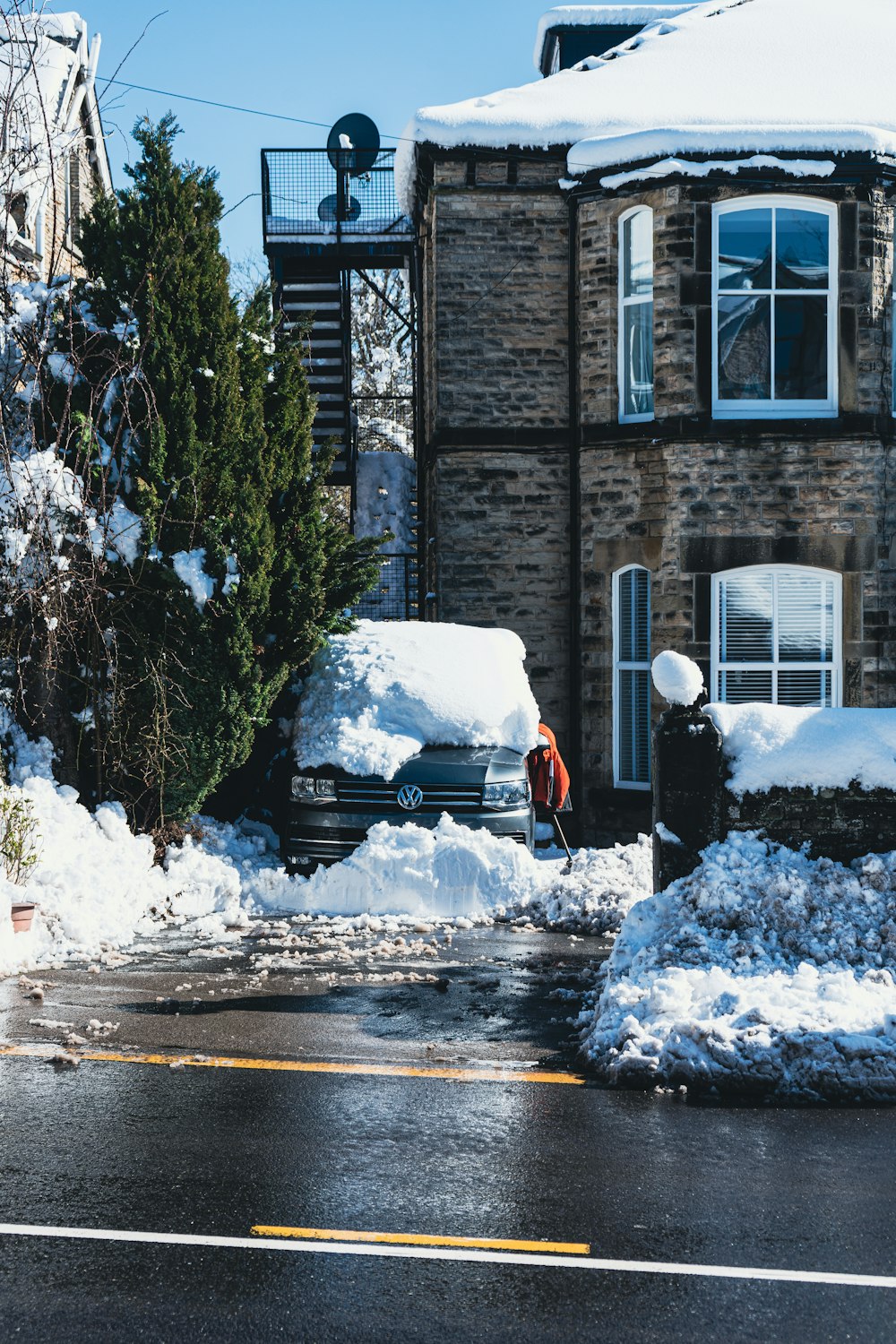 a car parked in front of a house covered in snow