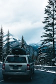 Luxury SUV parked with snowy alpine mountains in the background at sunset.