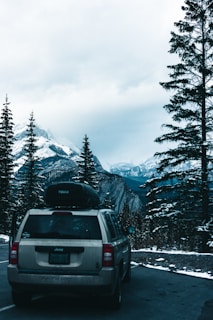 A sleek luxury SUV parked on a snowy alpine road with majestic mountains in the background.