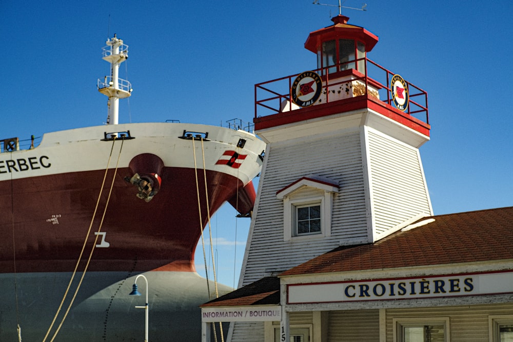 a large boat sitting in front of a lighthouse