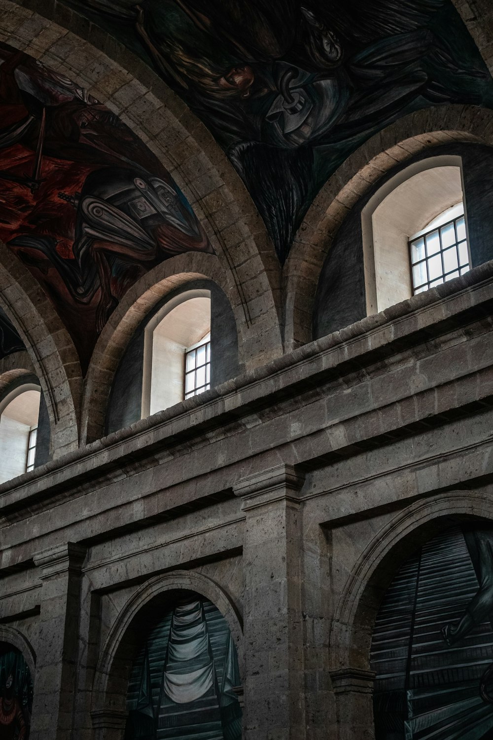 a large building with arched windows and paintings on the walls