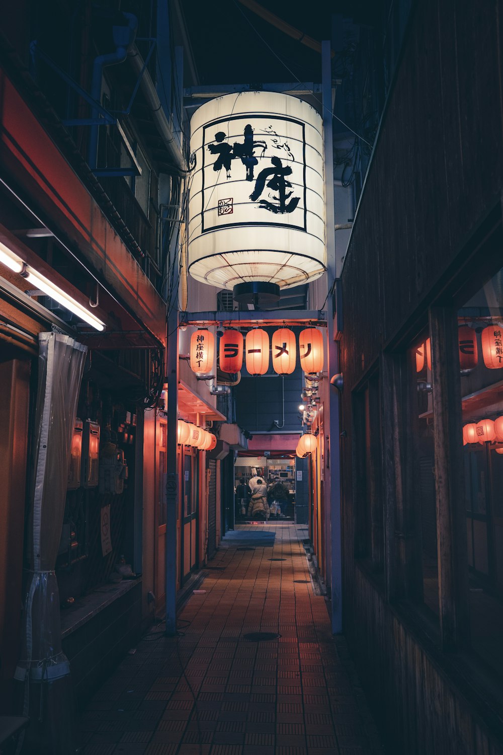 a narrow alley with lanterns hanging from the ceiling