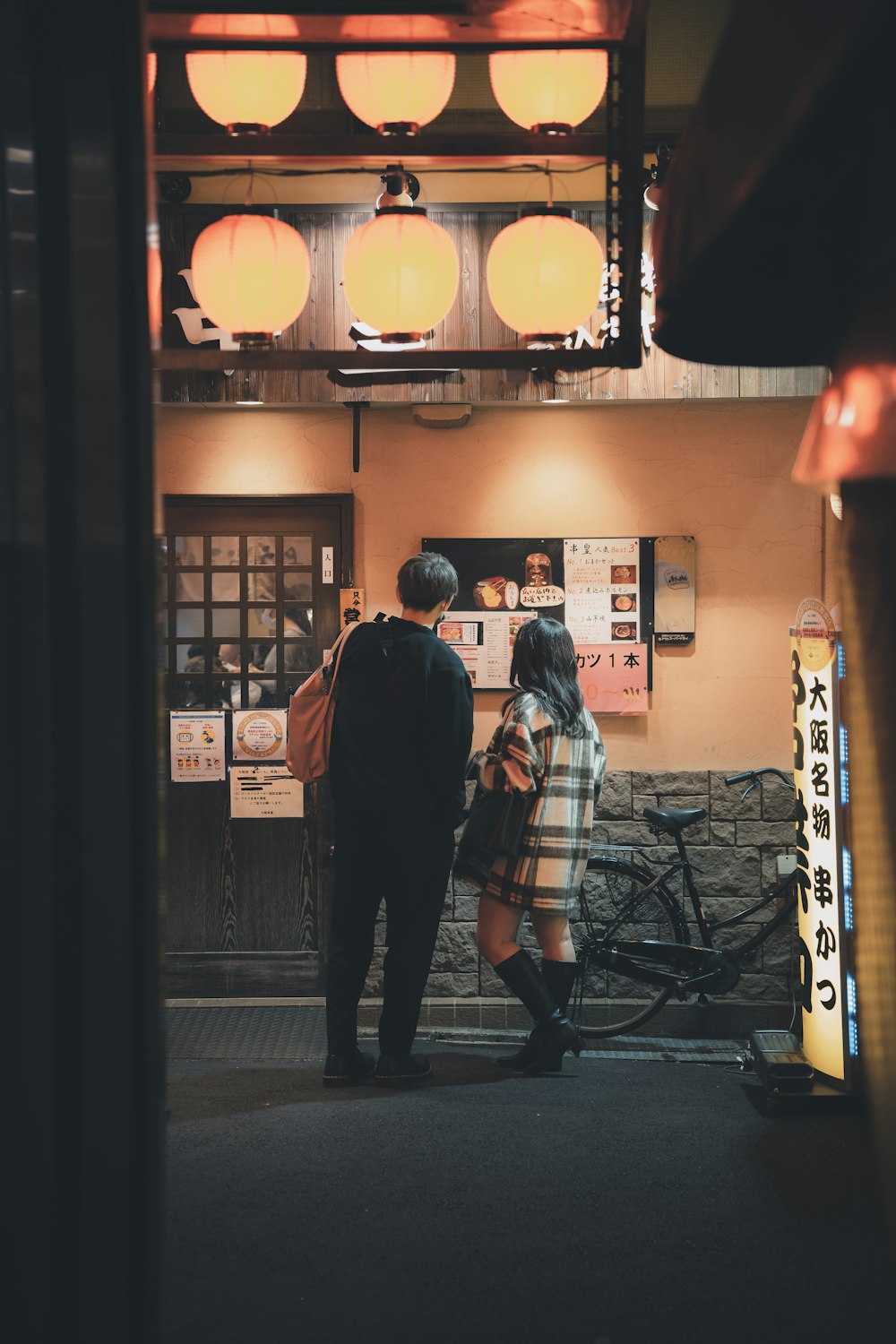 a man and a woman standing in front of a restaurant