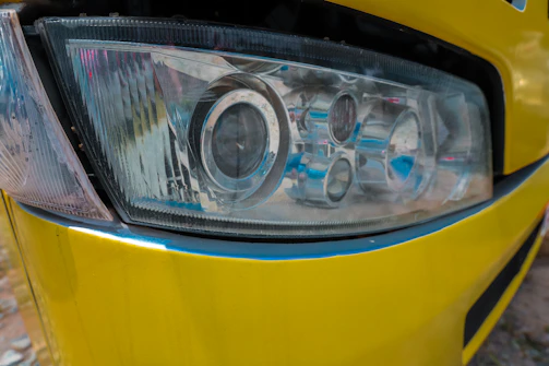 a close up of a headlight on a yellow car
