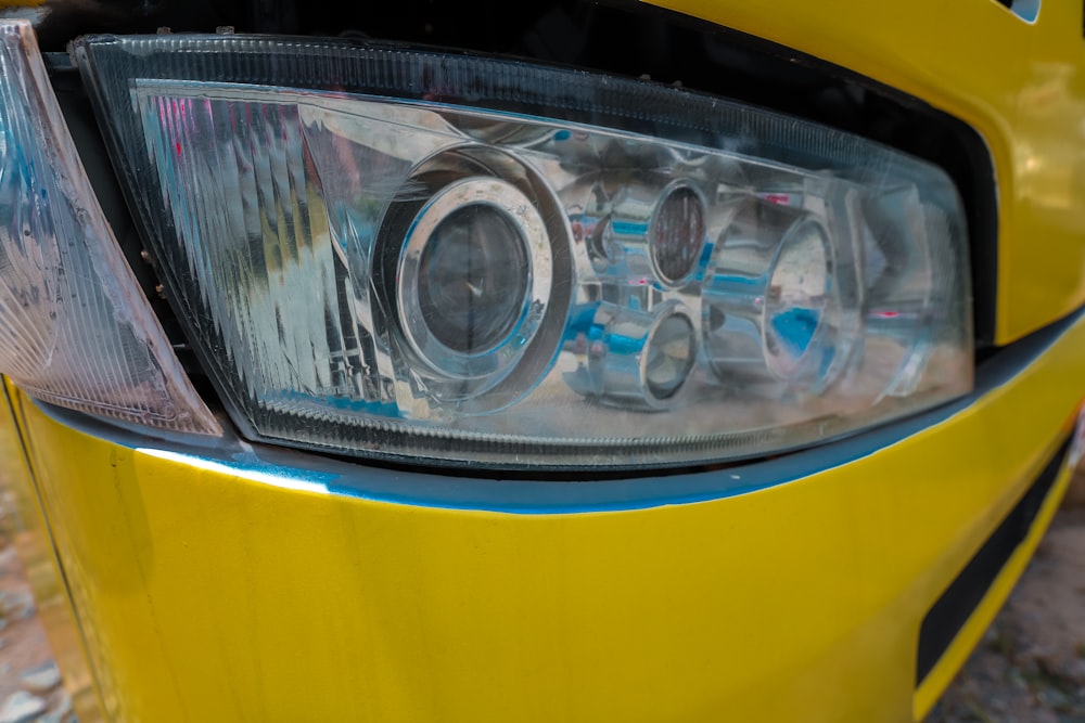 a close up of a headlight on a yellow car