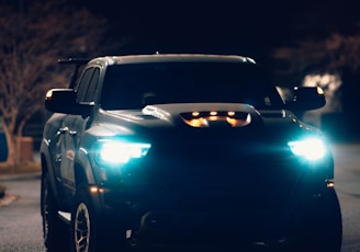 a black truck driving down a street at night