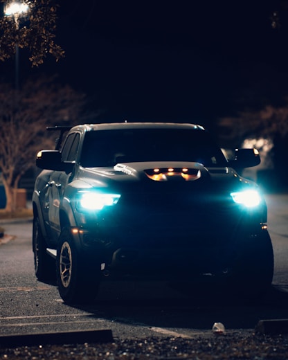 a black truck driving down a street at night