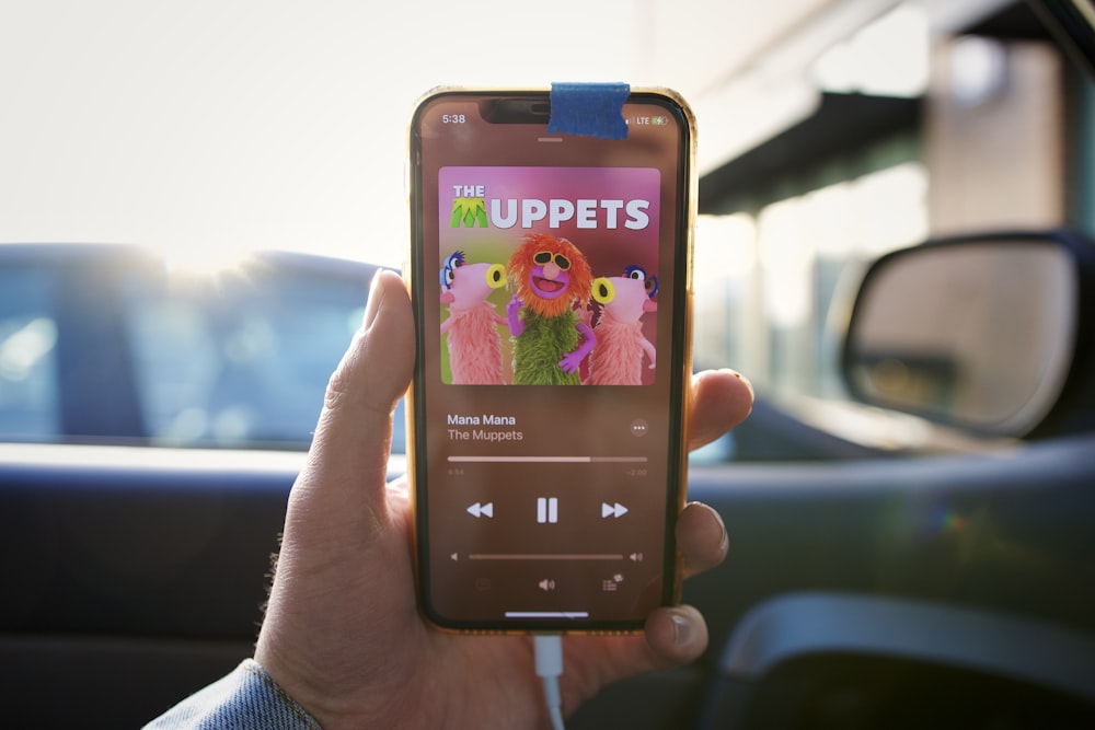 a person holding up a cell phone with the muppets on it