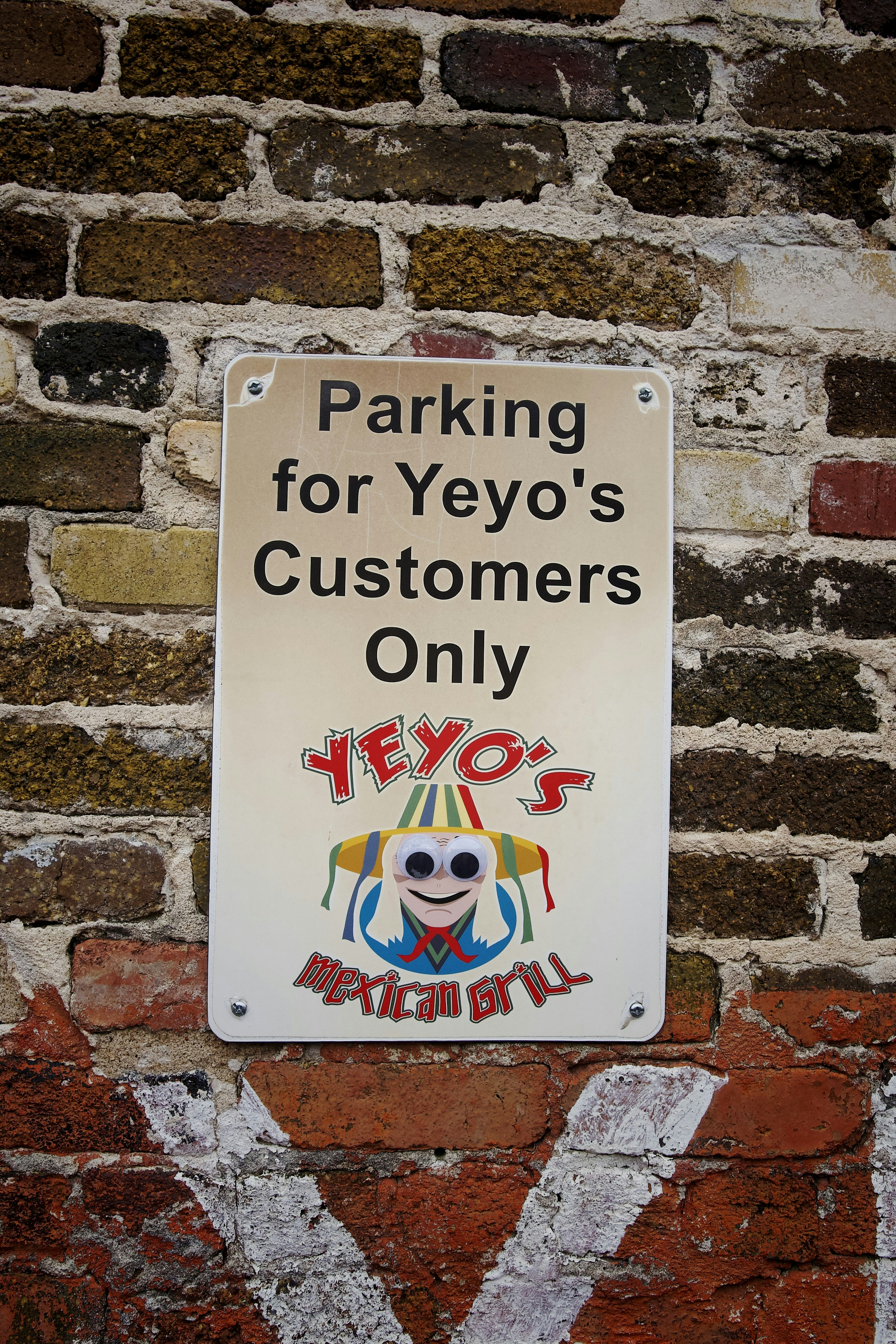 a sign on a brick wall stating parking for yeyo's customers only