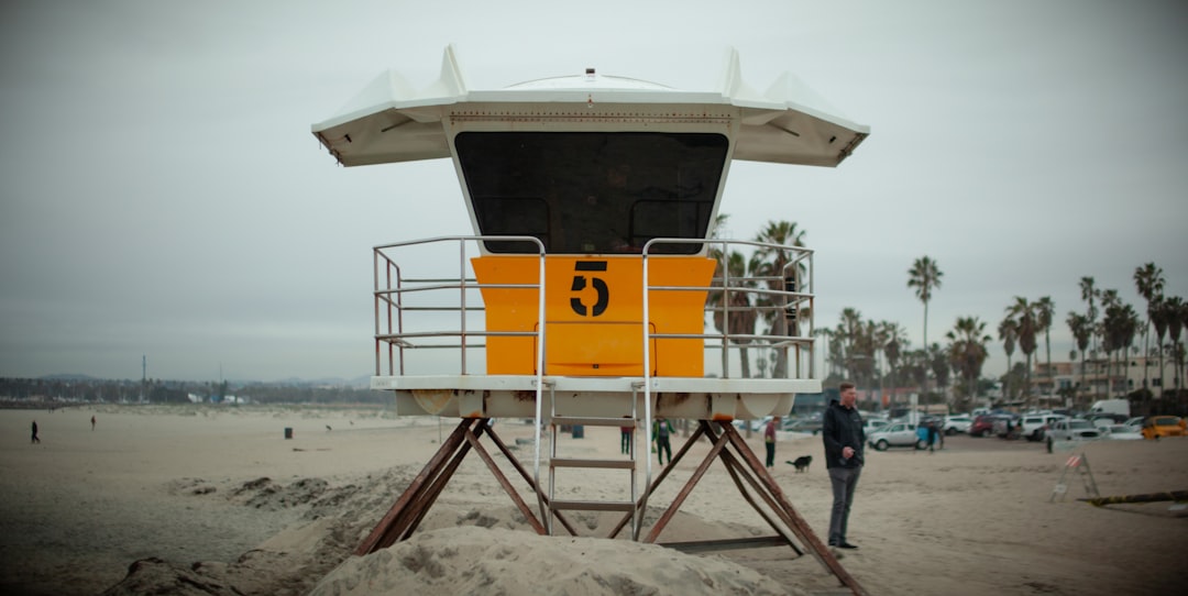 a lifeguard tower on the beach with a man standing next to it