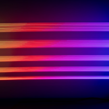Horizontal neon lights in shades of purple, pink, and red create a vivid and futuristic visual effect against a dark background.