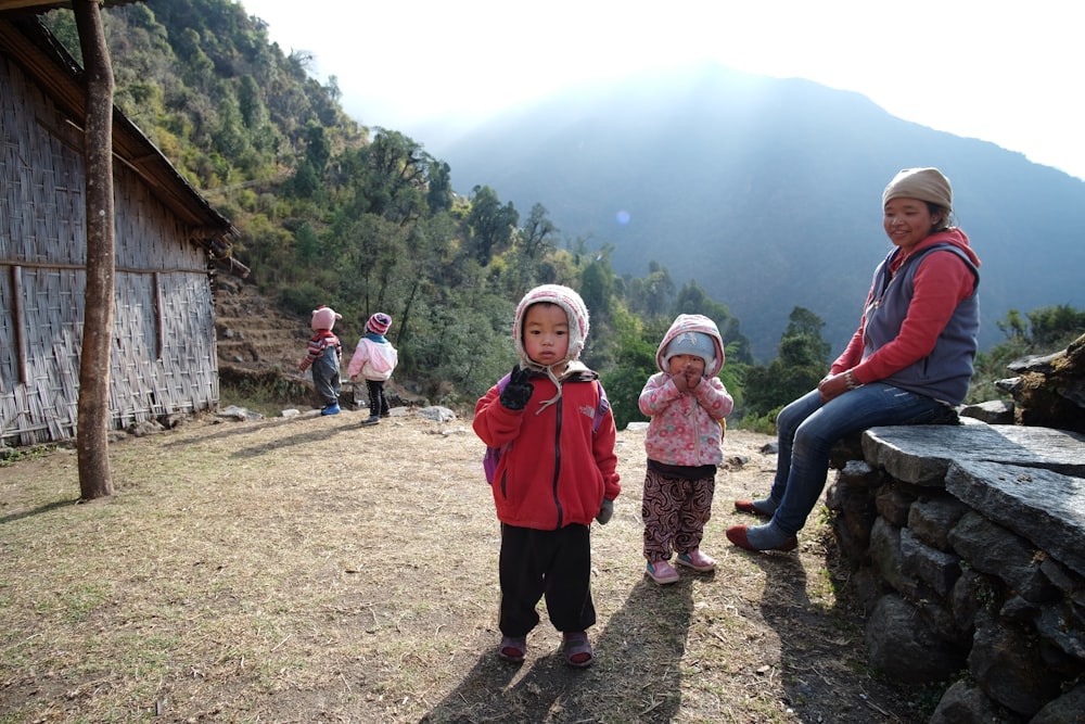 a group of children standing on top of a grass covered hillside