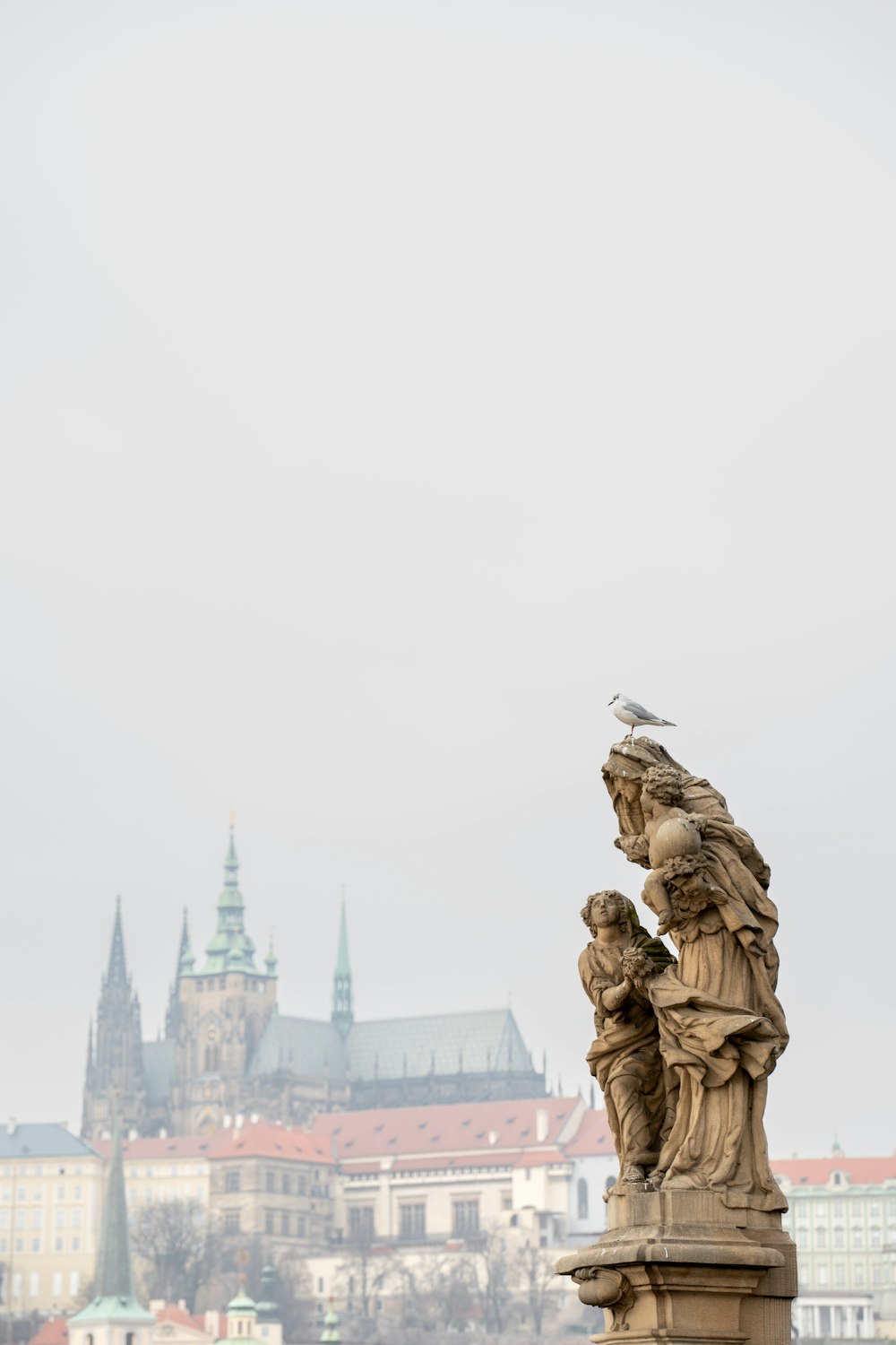 a bird perched on top of a statue in front of a castle