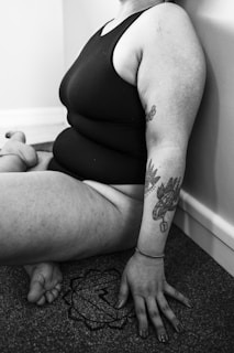 a woman sitting on the floor with a tattoo on her arm