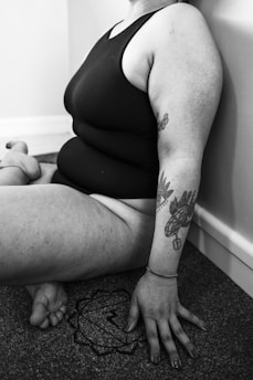 a woman sitting on the floor with a tattoo on her arm