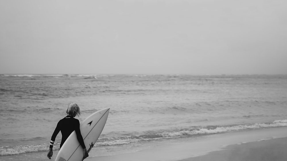 une personne marchant sur la plage avec une planche de surf