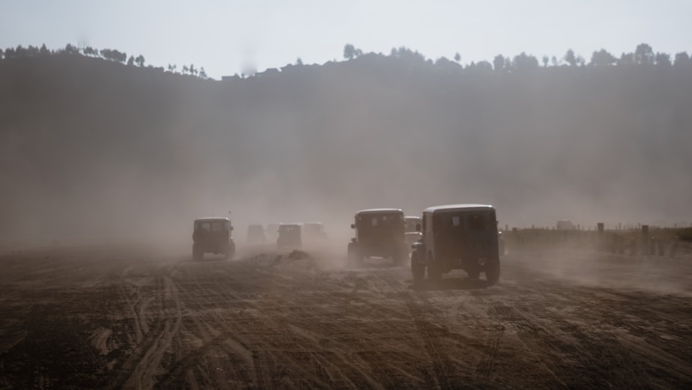 um grupo de caminhões dirigindo por uma estrada de terra