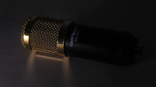 A sleek microphone illuminated by soft blue and gray lighting in a dark studio setting.