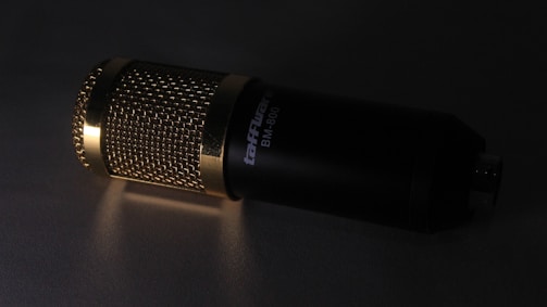 A sleek, dark-themed studio microphone with warm ambient lighting.