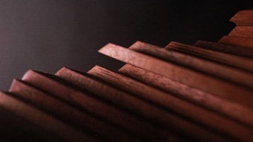 A close-up view of several wooden planks arranged diagonally against a dark background, each with a polished surface and sharp rectangular edges.