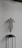 A wire sculpture of a human torso is displayed on a minimalist black stand. The sculpture has a hollow, mesh-like structure, showcasing the contours of a female torso without arms or a head. It is set against a plain, light-colored wall, creating a stark contrast.