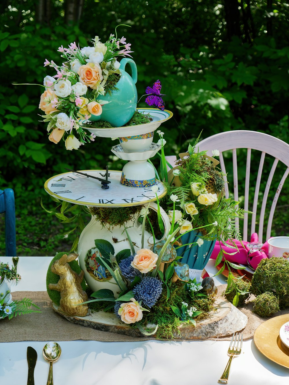 a table topped with a three tiered vase filled with flowers