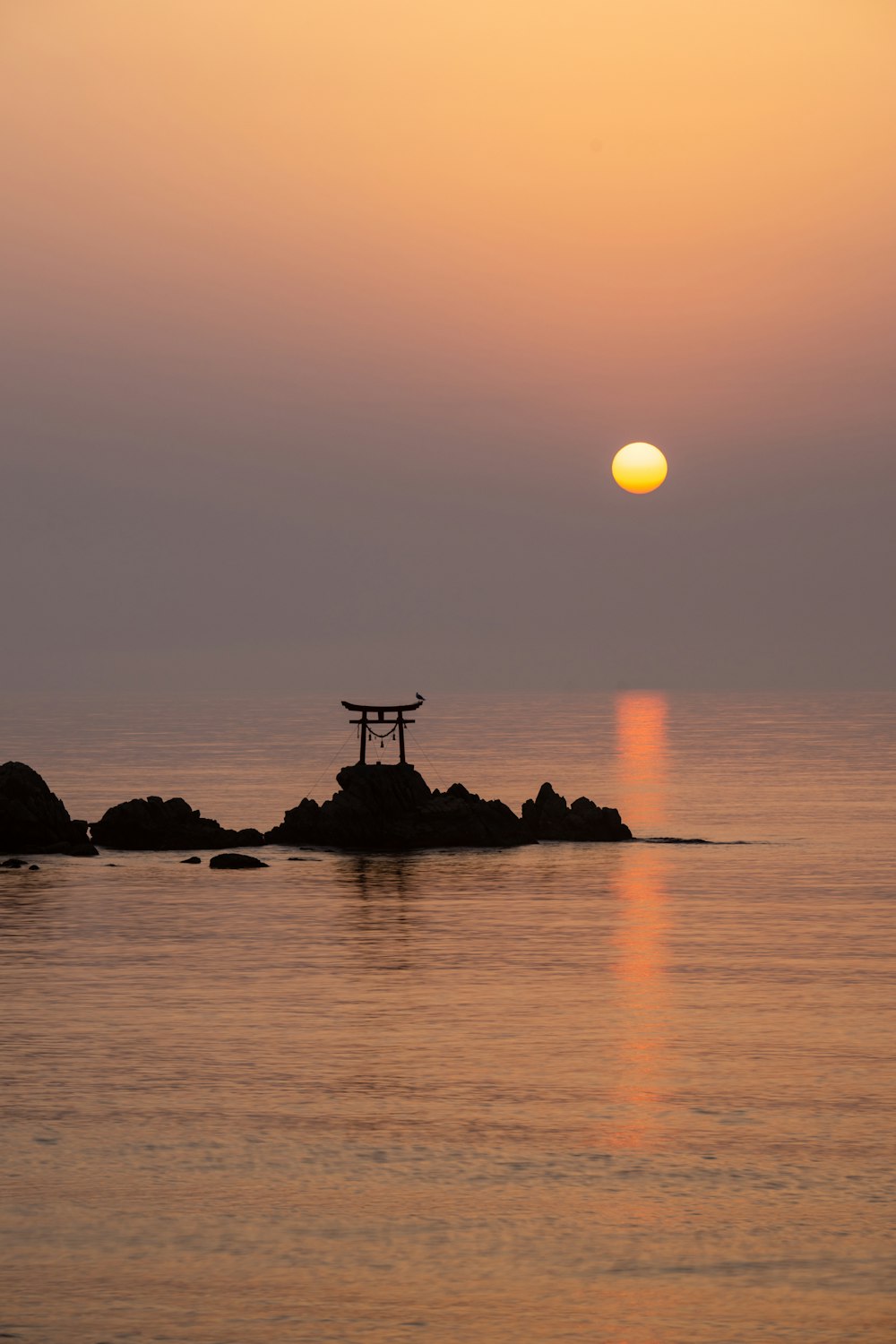 the sun is setting over a small island in the ocean