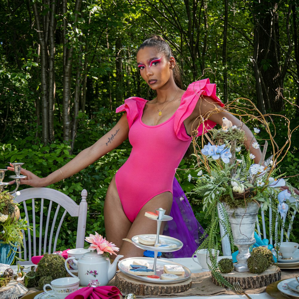 a woman in a pink swimsuit standing next to a table