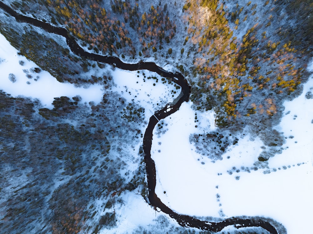 an aerial view of a river running through a snow covered forest