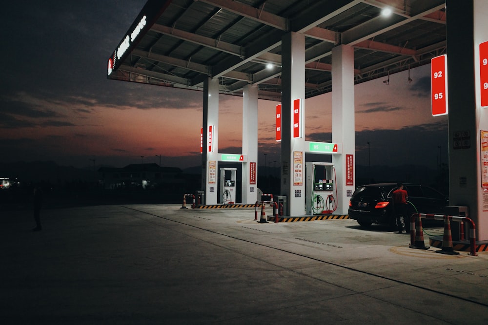 a gas station at night with a car parked at the gas pump