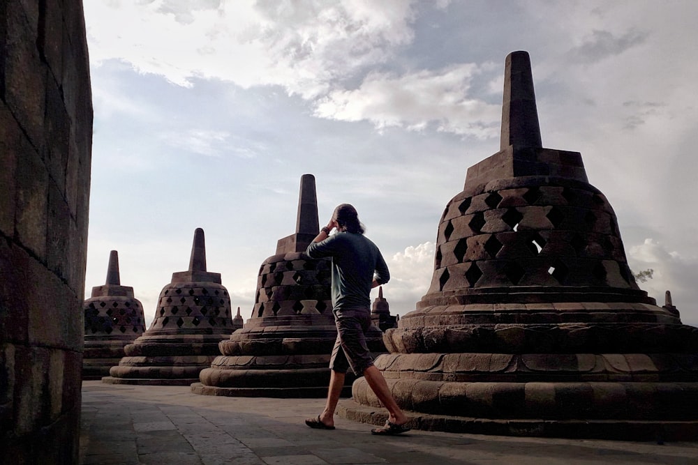 a man walking past a large stone structure