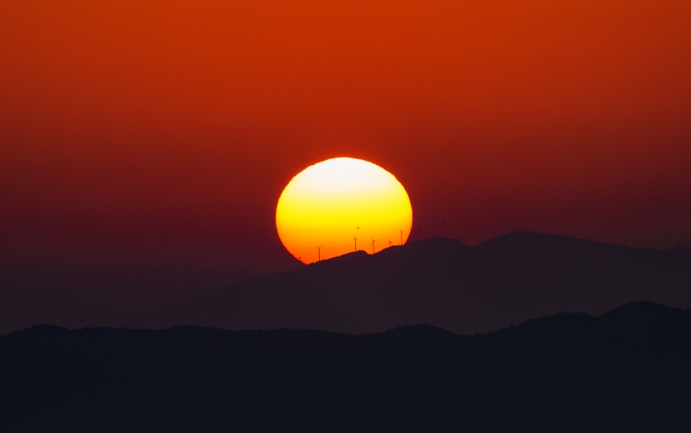 the sun is setting over a mountain range