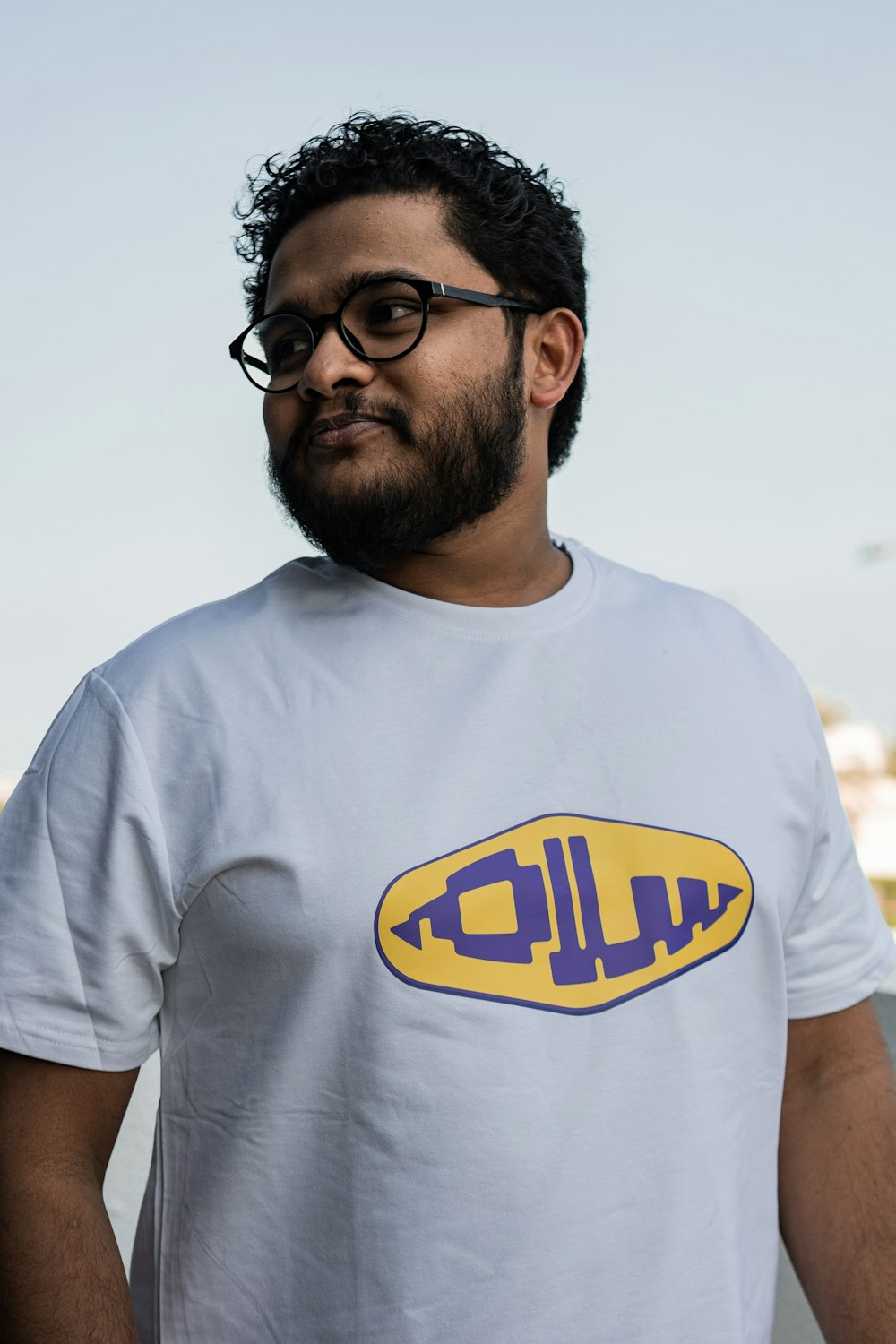 a man wearing a white shirt with a yellow and purple logo