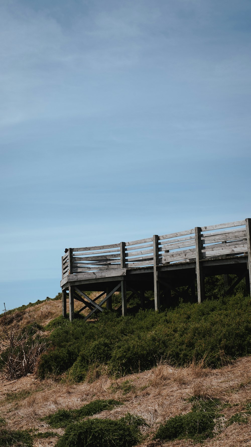 a wooden bench sitting on top of a grass covered hillside