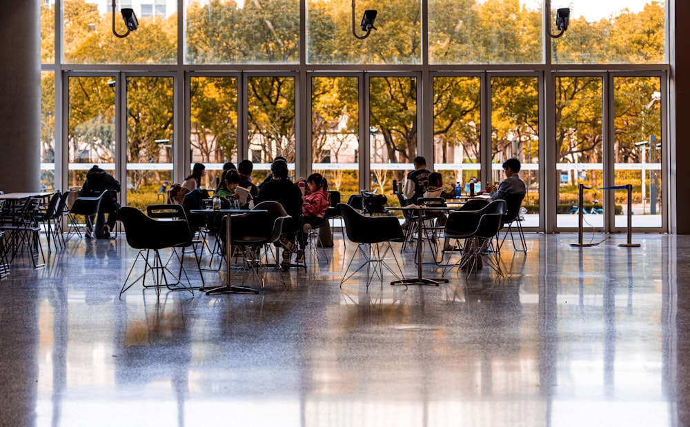 a group of people sitting at tables in front of a window