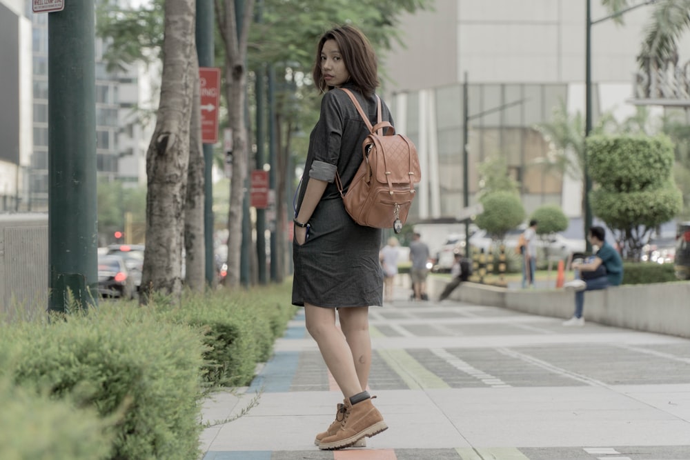 a woman walking down a sidewalk with a backpack on her back