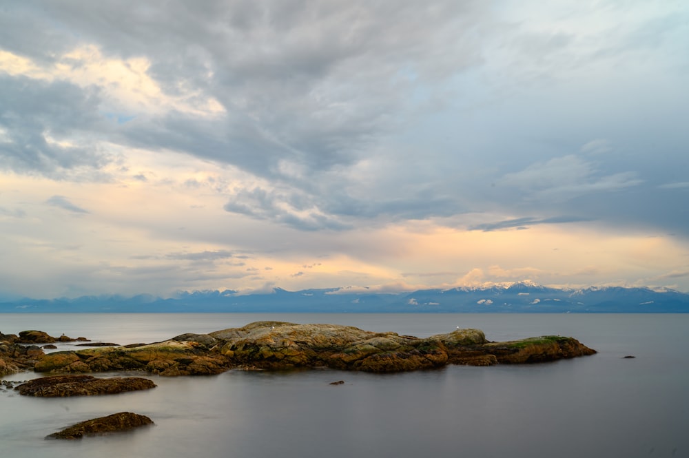 a body of water surrounded by rocks under a cloudy sky