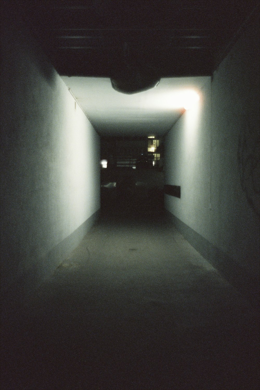 a dark hallway with a light at the end of it