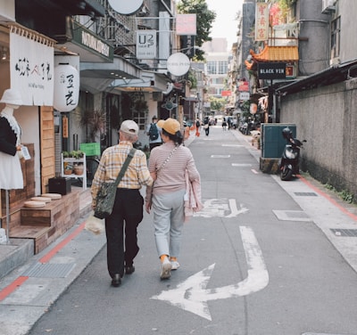 A serene scene of a mature couple enjoying a leisurely walk through a charming European village street.