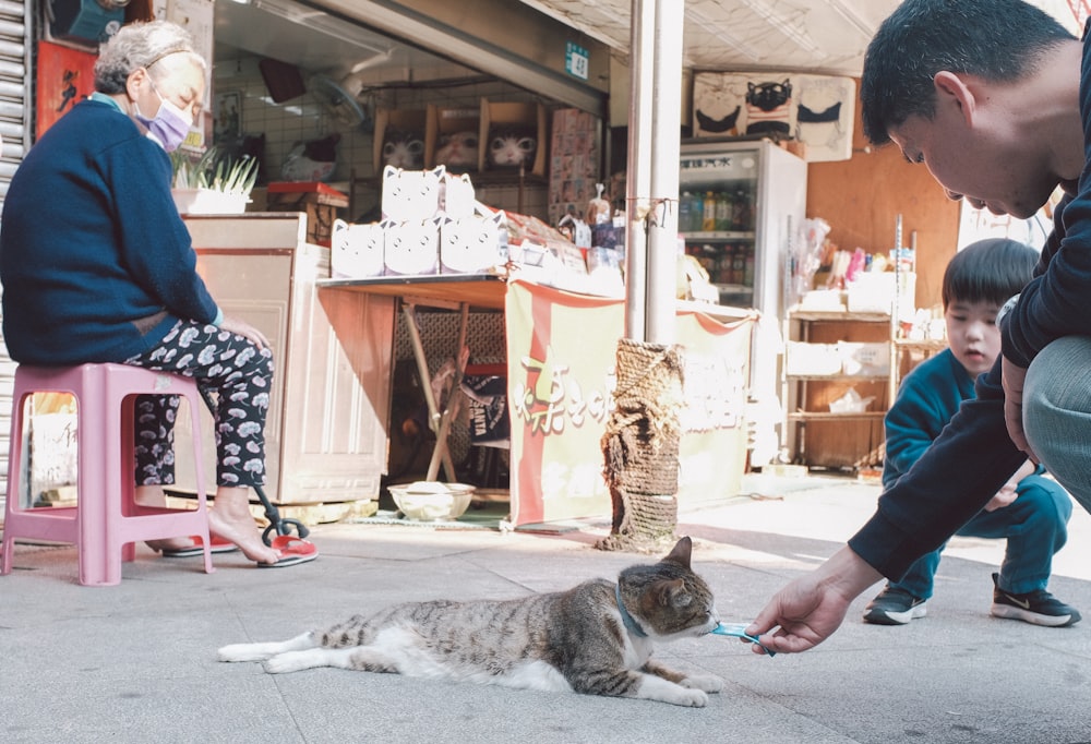a man is petting a cat on the street