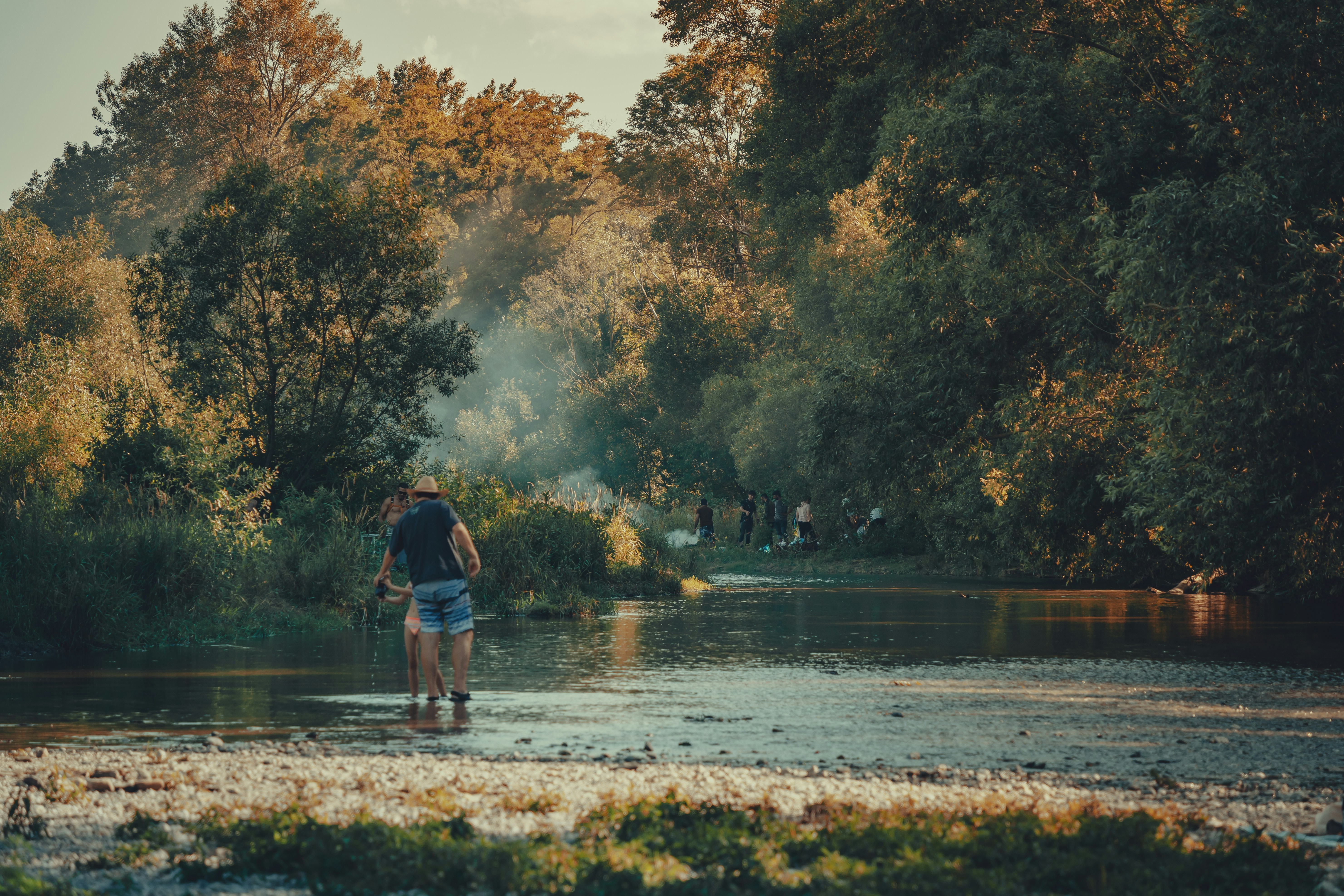 a person walking through a river with trees in the background