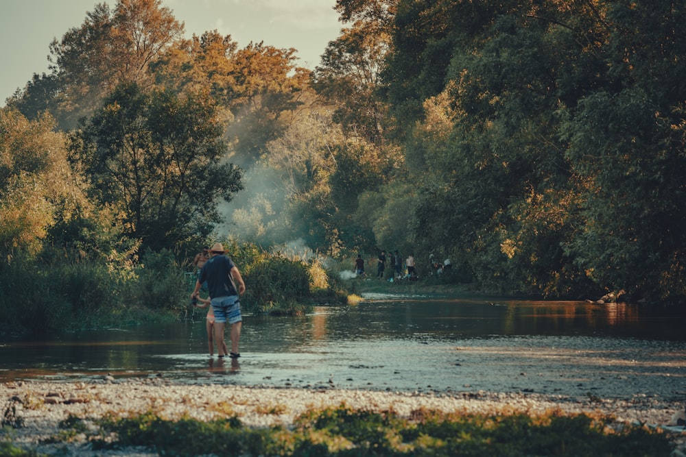 uma pessoa andando através de um rio com árvores ao fundo