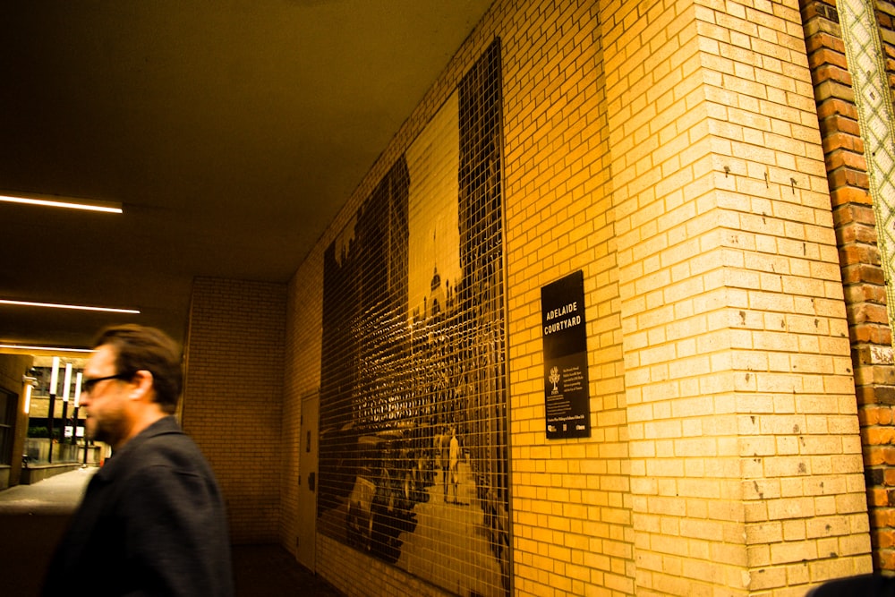 a man walking past a yellow brick wall
