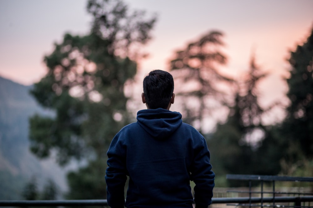 a man standing in front of a fence with trees in the background