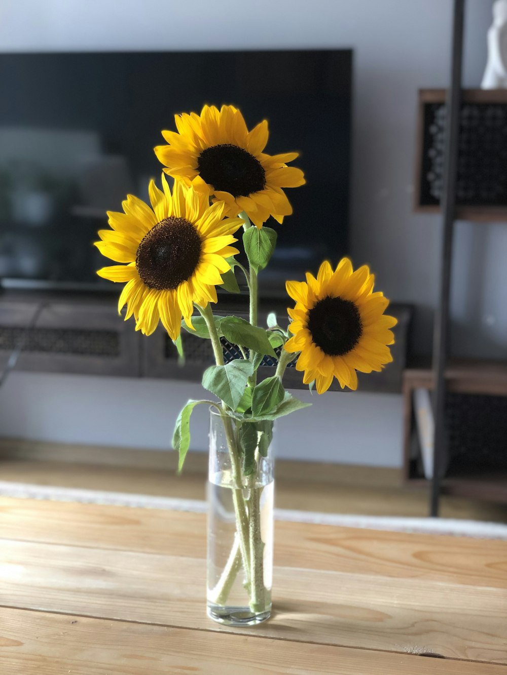 a vase filled with yellow sunflowers on top of a wooden table